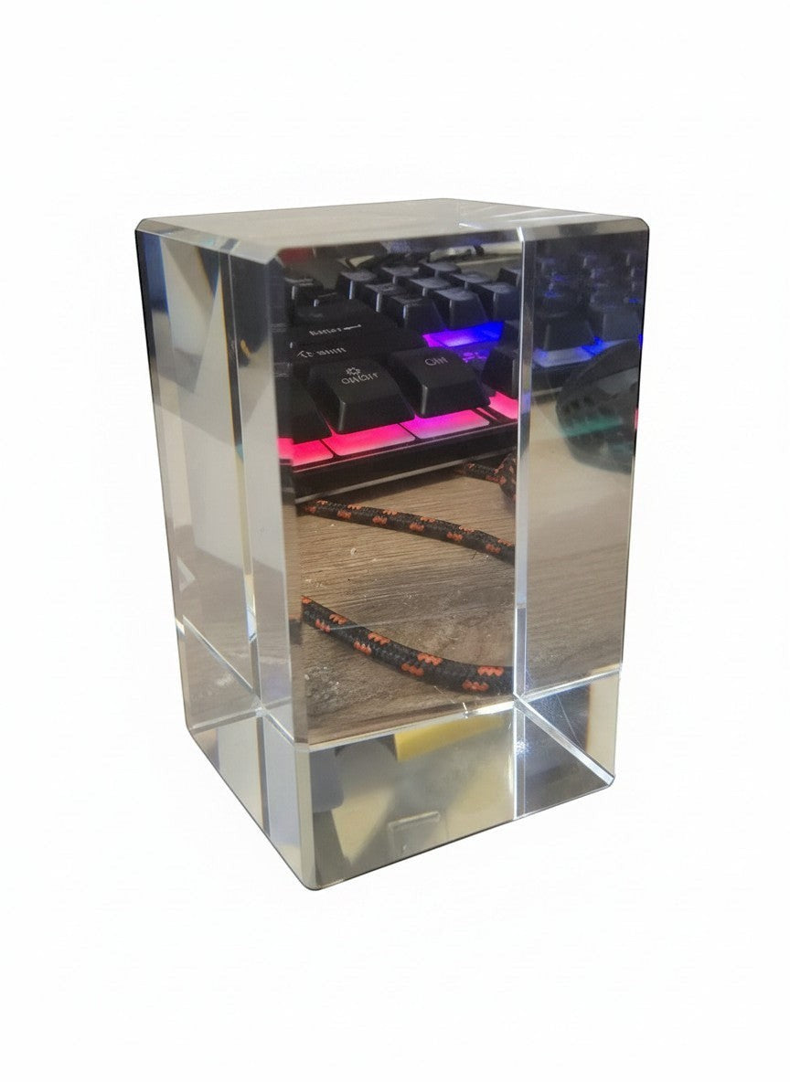 Papa Tee's clear crystal cube paperweight reflecting a keyboard with RGB lighting and a braided cord.
