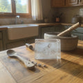 Papa Tee's clear crystal engraving of Jesus reaching out, set on a wooden table with rustic kitchen background.