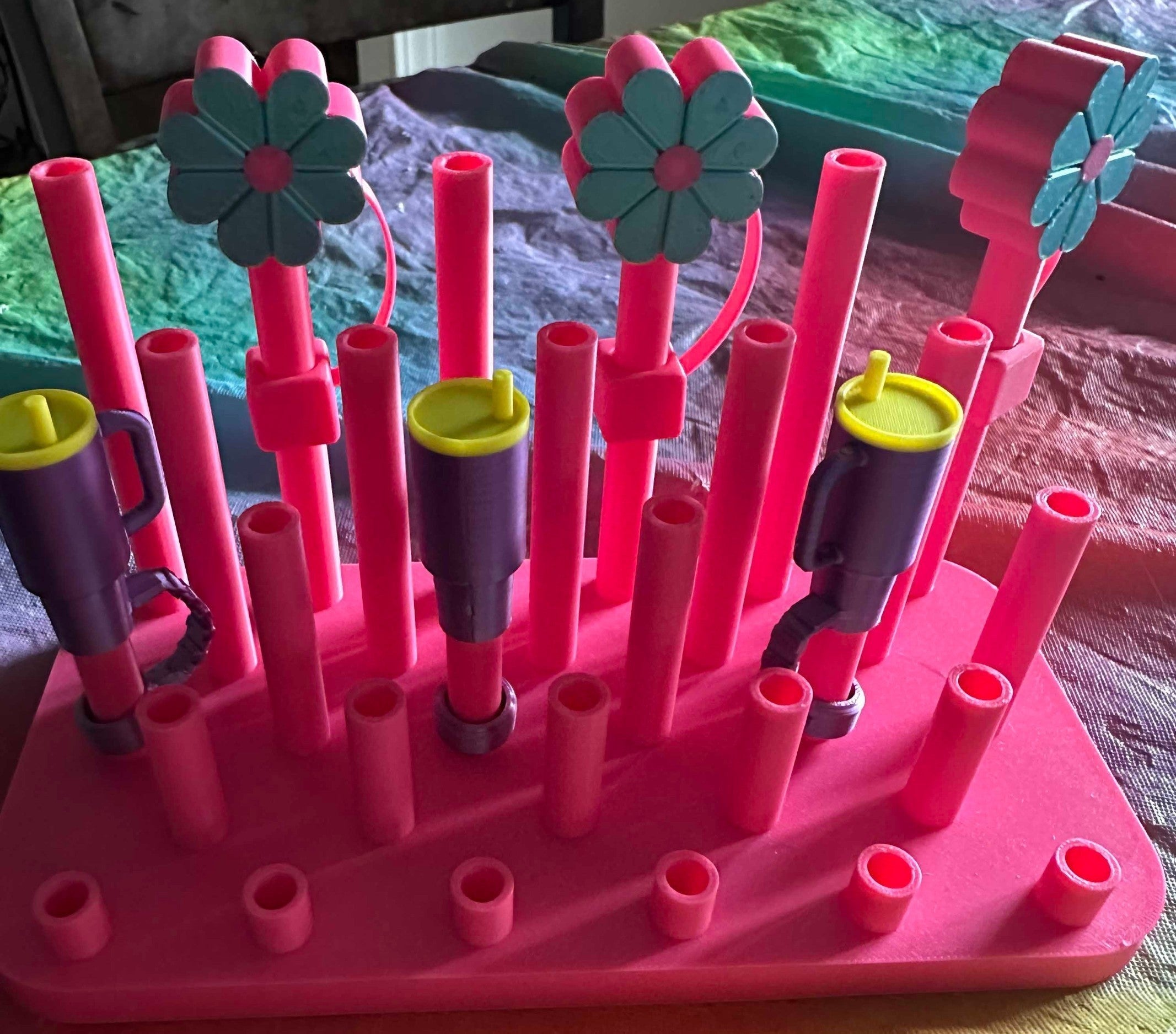 Papa Tee's pink baby bottle drying rack with purple cups and teal flower accents. Holds bottles, cups, and accessories.